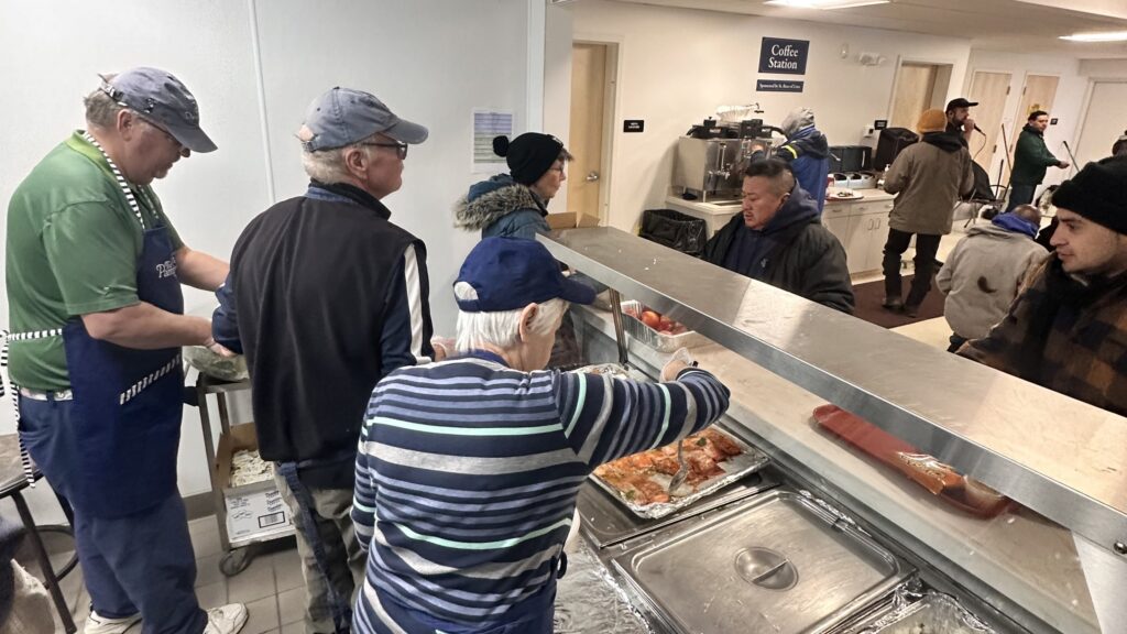 Volunteers at the Thomas Merton Family Center, a program of Catholic Charities of Fairfield County, work in the facility's kitchen to serve lunch to waiting clients.