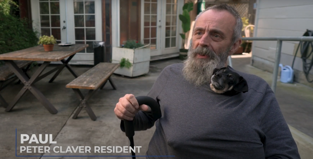 Paul, Peter Claver Resident wearing gray sweater and holding a small dog.