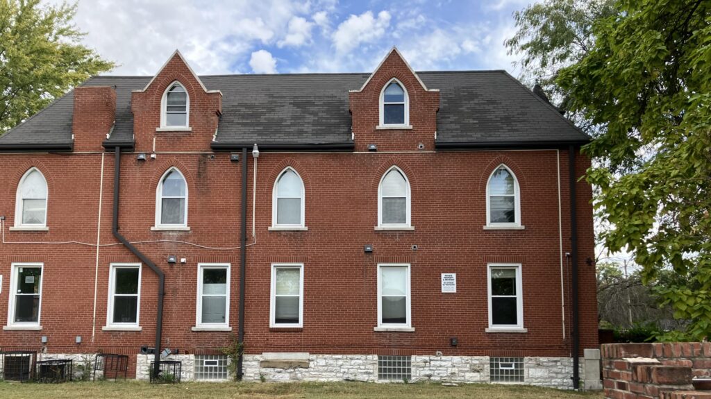 Three story red brick building with 13 white windows